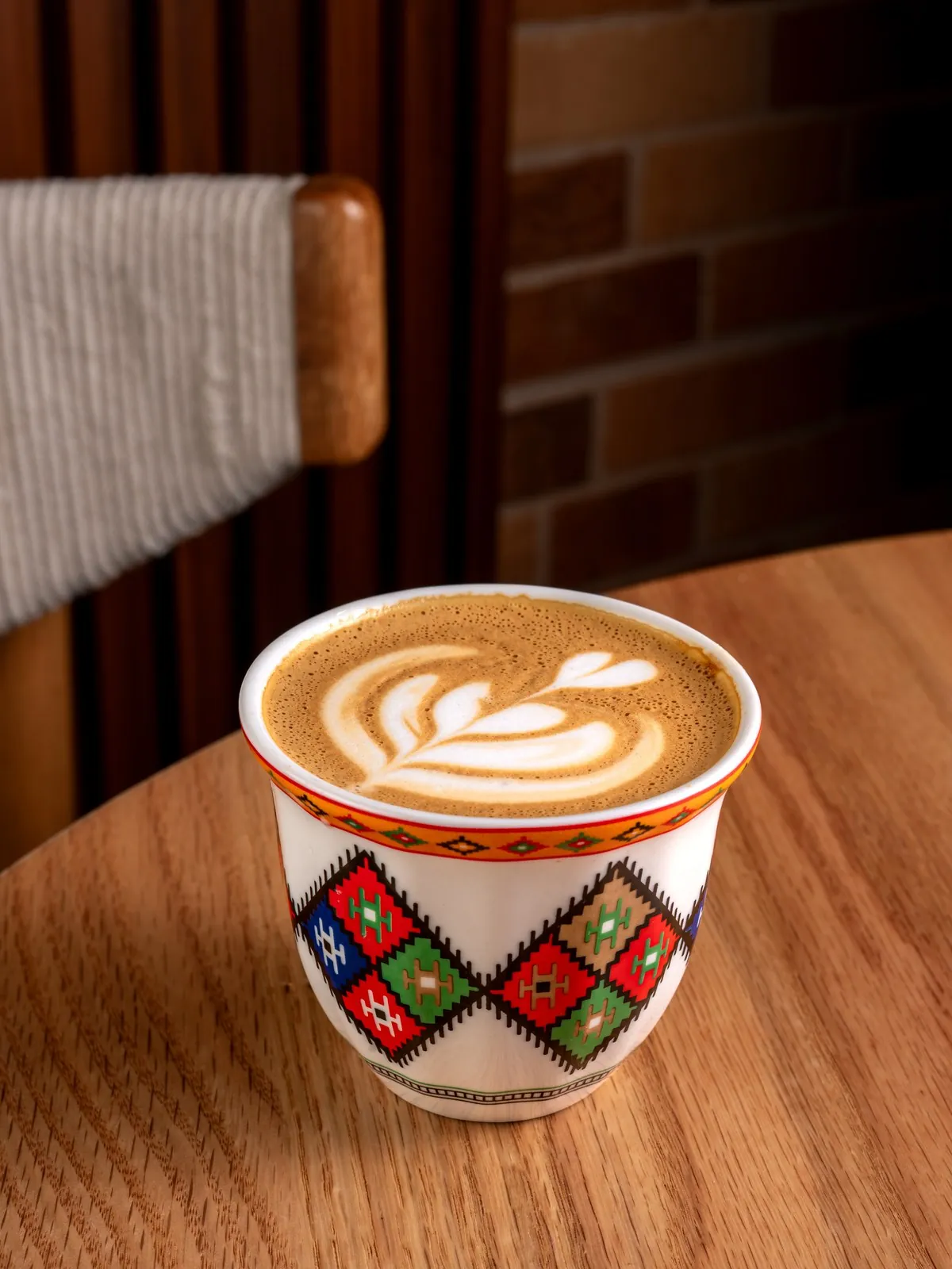 A latte with leaf art in a sadu patterned cup