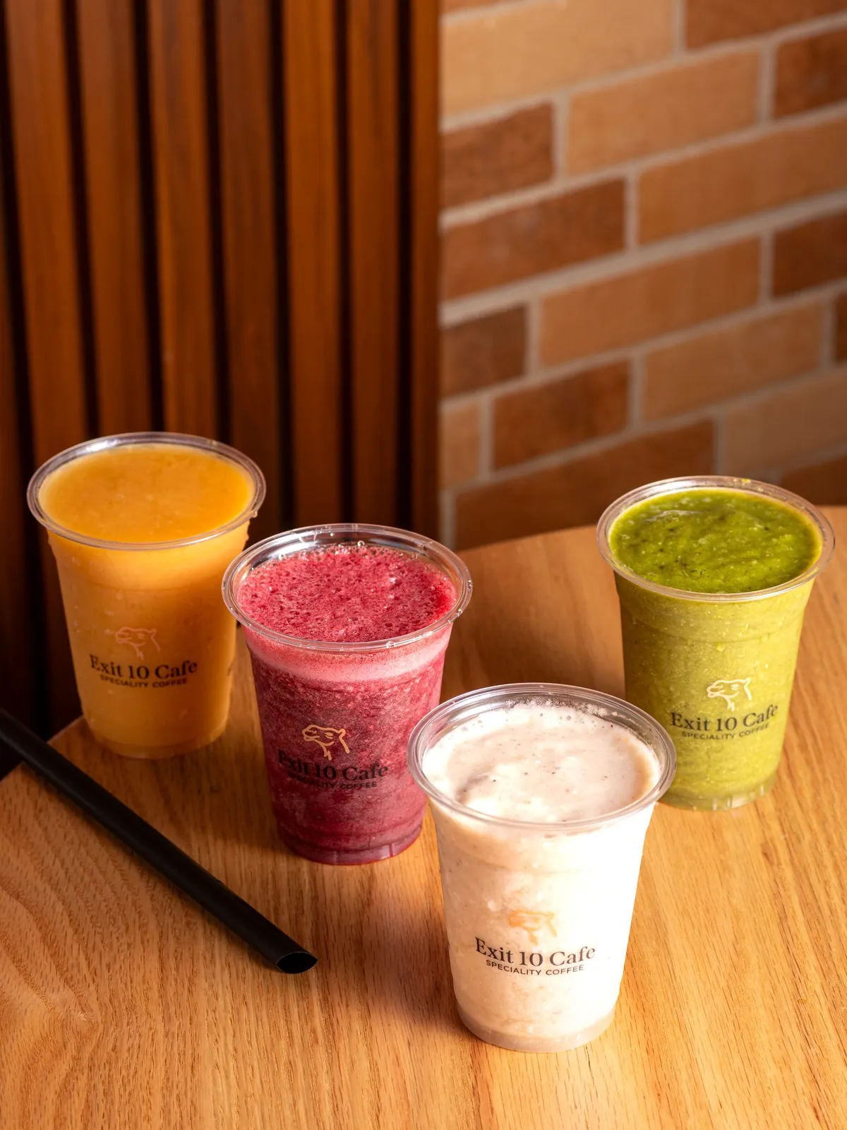 Four smoothies in Exit 10 cups on a wooden table